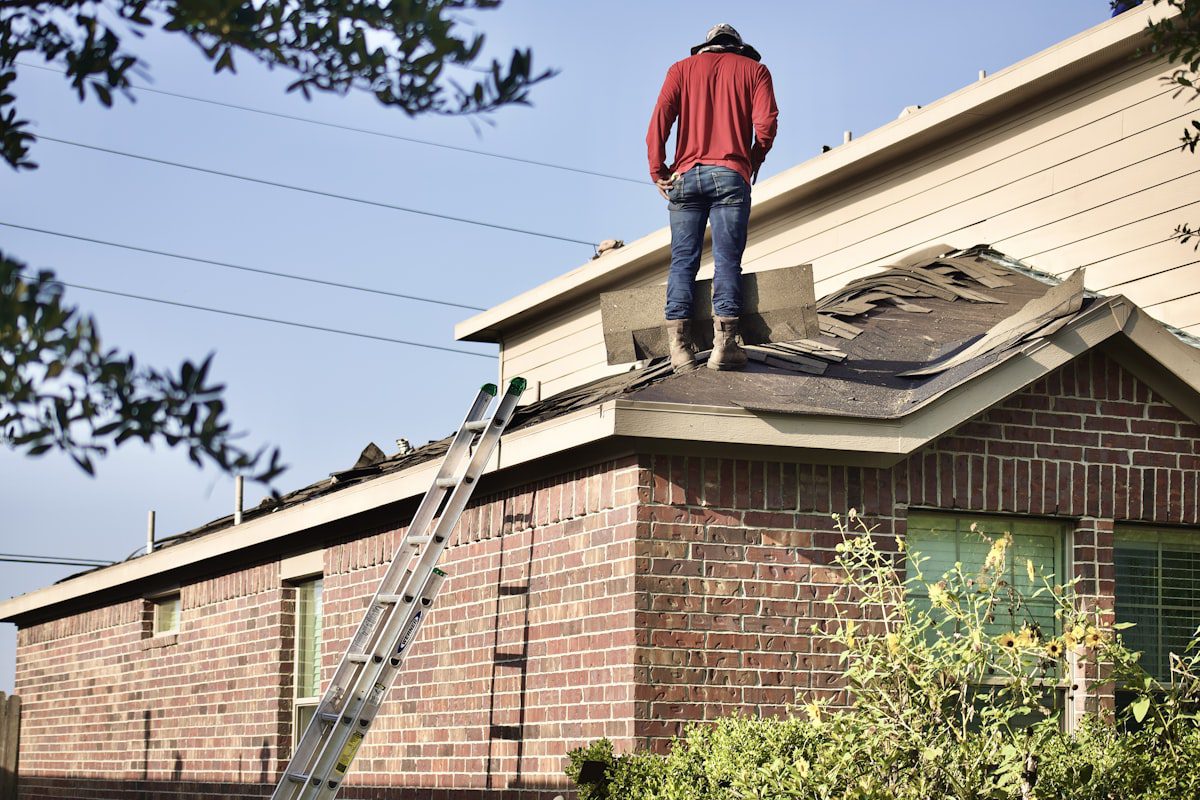Roofing worker removing old shingles during a roof replacement